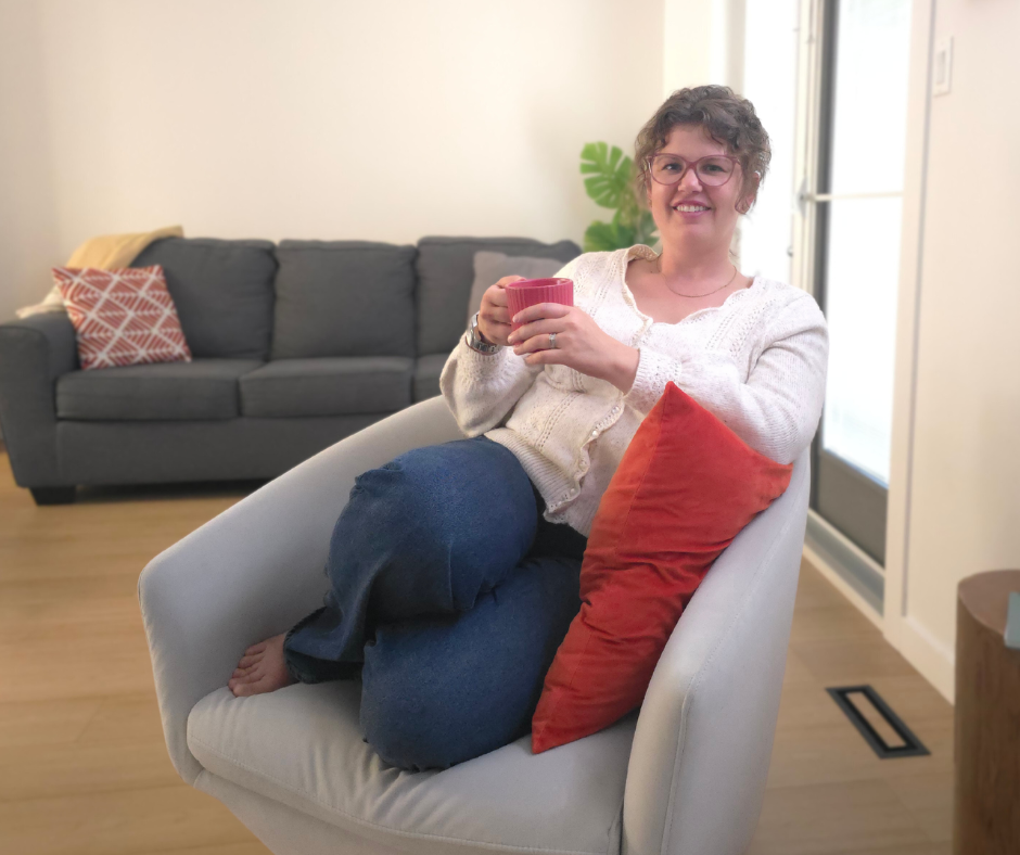 Christine Sander, founder of Seek Surrender Collective, smiling and holding a coffee mug in a light-filled, cozy space—representing calm clarity and authentic connection.